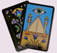 Cryptic card from the Initiates Oracle featuring the all-seeing eye above a pyramid framed by colorful ceremonial pillars and desert flowers