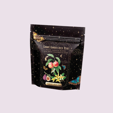 A stand-up pouch of Magic Hour Cosmic Carven Iced Teas on a soft pink background. The packaging is black with a starry night design, gold decorative borders, and an illustration of peach, fig, and yellow flowers.