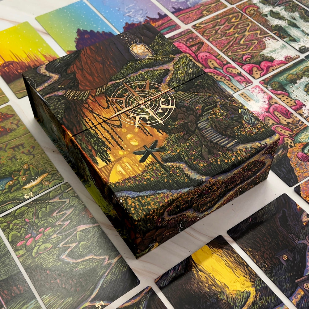 Close-up of Oracle of Many Paths magnetic closure box with rose gold compass design and detailed landscape artwork.