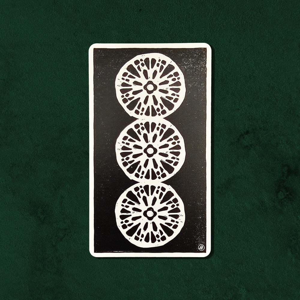 Three of Coins (Deux de Deniers) card from the Lux Tarot, featuring three circular coin symbols in UUSI's hand-carved linocut style.